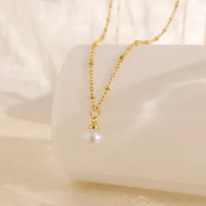Detaillierte Ansicht einer goldenen Halskette mit Perlenanhänger und Perlenkette.