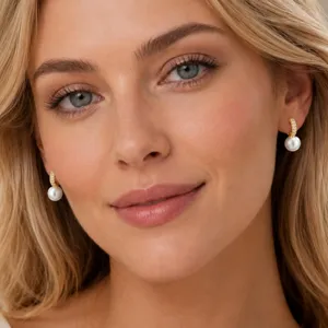 Nahaufnahme eleganter goldfarbener Perlenohrringe, getragen von einem Model im Licht