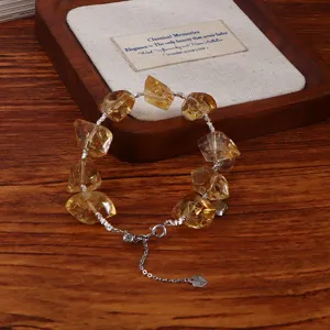Natürliches Citrin-Kristallarmband mit Silberherz-Anhänger auf einem Holztablett präsentiert