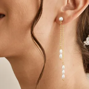 Detailansicht eleganter langer Quastenohrringe mit weißen Perlen und Goldkette