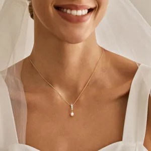 Detailaufnahme einer eleganten Goldkette mit Perlenanhänger an einem Brautmodel