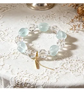 Detaillierte Makroansicht von Armband aus grünem Fluorit und Kristallperlen auf weißer Spitze