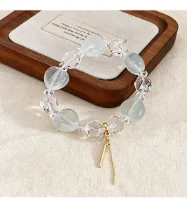 Detailansicht eines Armbands aus grünem Fluorid und weißem Kristall mit goldenem Anhänger