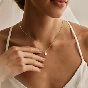 Elegante Detailaufnahme einer goldenen Halskette mit einem Tropfenperlen-Anhänger