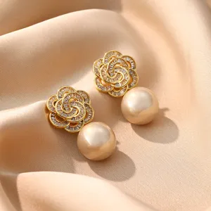 Detailaufnahme eleganter Goldblumen-Ohrringe mit Zirkonia und hängenden Perlen