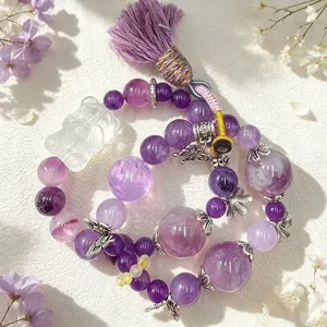 Nahaufnahme eines lila Kristallarmbands mit klarem Fuchs-Anhänger und eleganter Seidenquaste