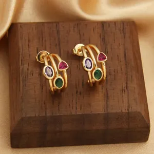 Detailaufnahme goldener Ohrringe mit bunten Zirkoniasteinen auf einem Holzständer