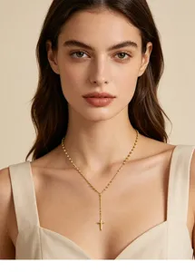 Elegante goldene Y-Halskette mit Kreuzanhänger an einem Model auf beigem Hintergrund