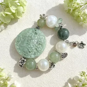 Elegantes Schmuckdetail mit geschnitztem grünem Jade-Anhänger und weißen Perlen.