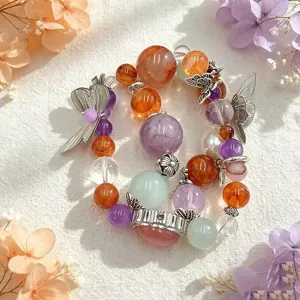 Detailaufnahme eines bunten Kristallarmbands mit eleganten silbernen Schmetterlingsanhängern