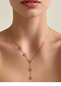 Detailaufnahme einer goldenen Y-Halskette mit fünf hohlen Herzanhängern an einem Model