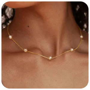 Detailansicht einer zarten goldenen Halskette mit funkelnden rund eingefassten Steinen.