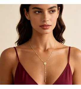 Elegante goldene Lariat-Halskette mit Kleeblatt-Anhänger an einem Model mit weinrotem Top.