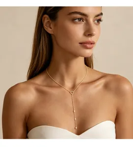 Detail einer eleganten goldenen Herz-Y-Kette mit weißen Perlen, getragen von einem Model