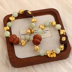 Nahaufnahme von Adlerholz- und Jadeperlenarmbändern auf einem Vintage-Holztablett
