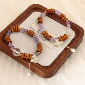 Makroaufnahme von Sandelholz und Amethyst Armband mit goldenem Schmetterling Perle Anhänger