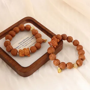 Detailansicht von zwei handgefertigten Holzperlenarmbändern mit Zieranhängern auf Holztablett.