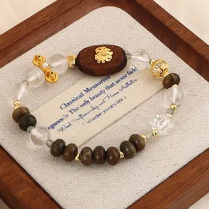 Detailansicht eines Armbands aus Naturholz und Kristall mit goldenem Blumenanhänger