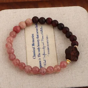 Detailansicht von handgefertigtem Sandelholz und Erdbeerquarz Perlenarmband auf Leinwand