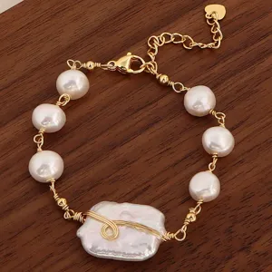 Makrodetail eines handgefertigten Süßwasserperlen-Armbands mit Golddrahtwicklung auf Holz