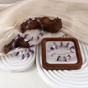 Makro-Detail von Amethyst- und Bergkristall-Armbändern auf einem hölzernen Display-Tablett.