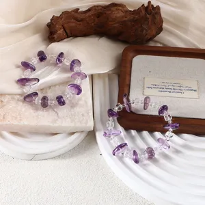 Nahaufnahme von Perlenarmbändern aus Amethyst und klarem Quarz auf Dekoration.