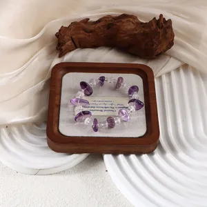 Nahaufnahme eines natürlichen Amethyst- und Bergkristall-Armbands auf Holztablett