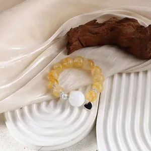 Detail des gelben Citrin-Perlenarmbands mit weißer Perle und schwarzem Herzanhänger