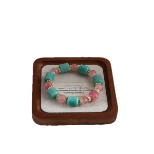 Natur-Amazonit- und Kirschblütenachat-Armband auf einem hochwertigen Holzdisplay-Tablett