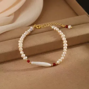 Elegantes Naturperlenarmband mit roten Achatperlen auf einem beigen Samttablett.