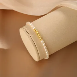 Nahaufnahme eines eleganten Perlenarmbands mit goldenen Perlen auf einem Displayständer.