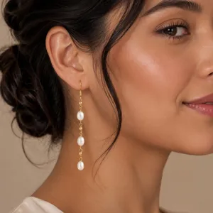 Elegante lange Hängeohrringe mit drei weißen Perlenimitaten an einer feinen Goldkette