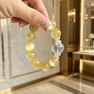 Nahaufnahme eines Armbands aus goldenem Lepidolith mit transparentem Kristall