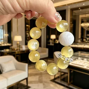 Nahaufnahme eines durchscheinenden goldenen Lepidolith-Armbands mit weißem Akzent.