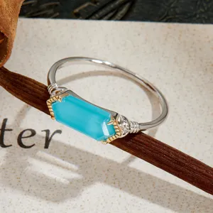 Close-up of a silver ring featuring a rectangular blue turquoise stone with gold accents.