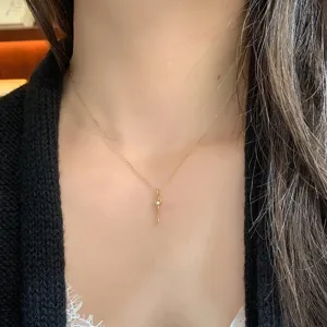 Dettaglio di una delicata collana con ciondolo a chiave dorata con pietra preziosa su modella