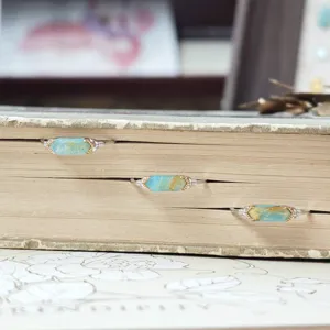 Macro view of three s925 silver rings with hexagonal blue-green stones in an old book