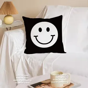 Cuscino decorativo nero con motivo smiley bianco per un comodo divano di casa.