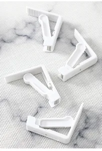 Dettaglio di 4 clip per tovaglia in plastica bianca per un fissaggio sicuro del tavolo