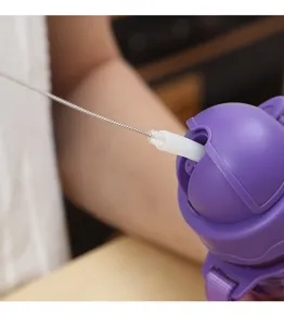 Gros plan d'une petite brosse de nettoyage de paille utilisée sur une gourde violette