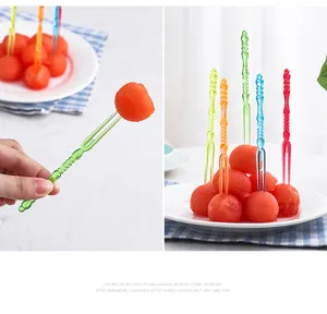 Detailed view of colorful plastic fruit forks piercing fresh watermelon balls on a plate