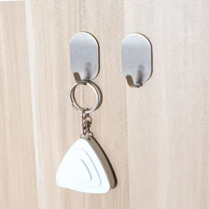 Zwei minimalistische ovale selbstklebende Wandhaken aus Edelstahl auf einer hellen Holzoberfläche