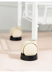 Close-up of black non-slip stoppers fixing white trolley wheels on a flat surface
