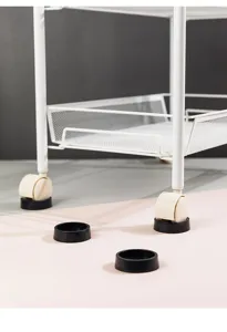 Durable black rubber furniture wheel stoppers for chairs and carts shown on a pink floor