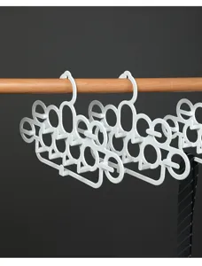 Detailopname van een witte plastic hanger voor dassen en riemen aan een houten kledingstang