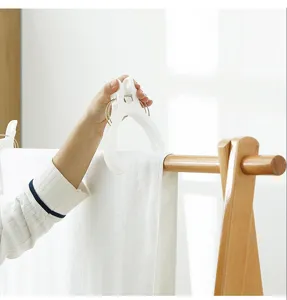 Große weiße Kunststoff-Bettdeckenklammer fixiert ein Handtuch auf einem Holzständer.