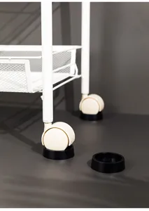Close-up of black anti-slip furniture caster cups holding white trolley wheels securely