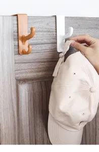 Nahaufnahme von Türhaken, die eine beige Baseballkappe an einer Holztür halten
