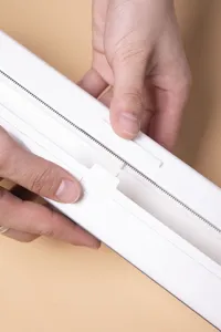Dettaglio di un distributore magnetico bianco per pellicola con lama di taglio scorrevole