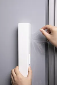 Vista dettagliata del dispenser magnetico bianco durante l'estrazione della pellicola.